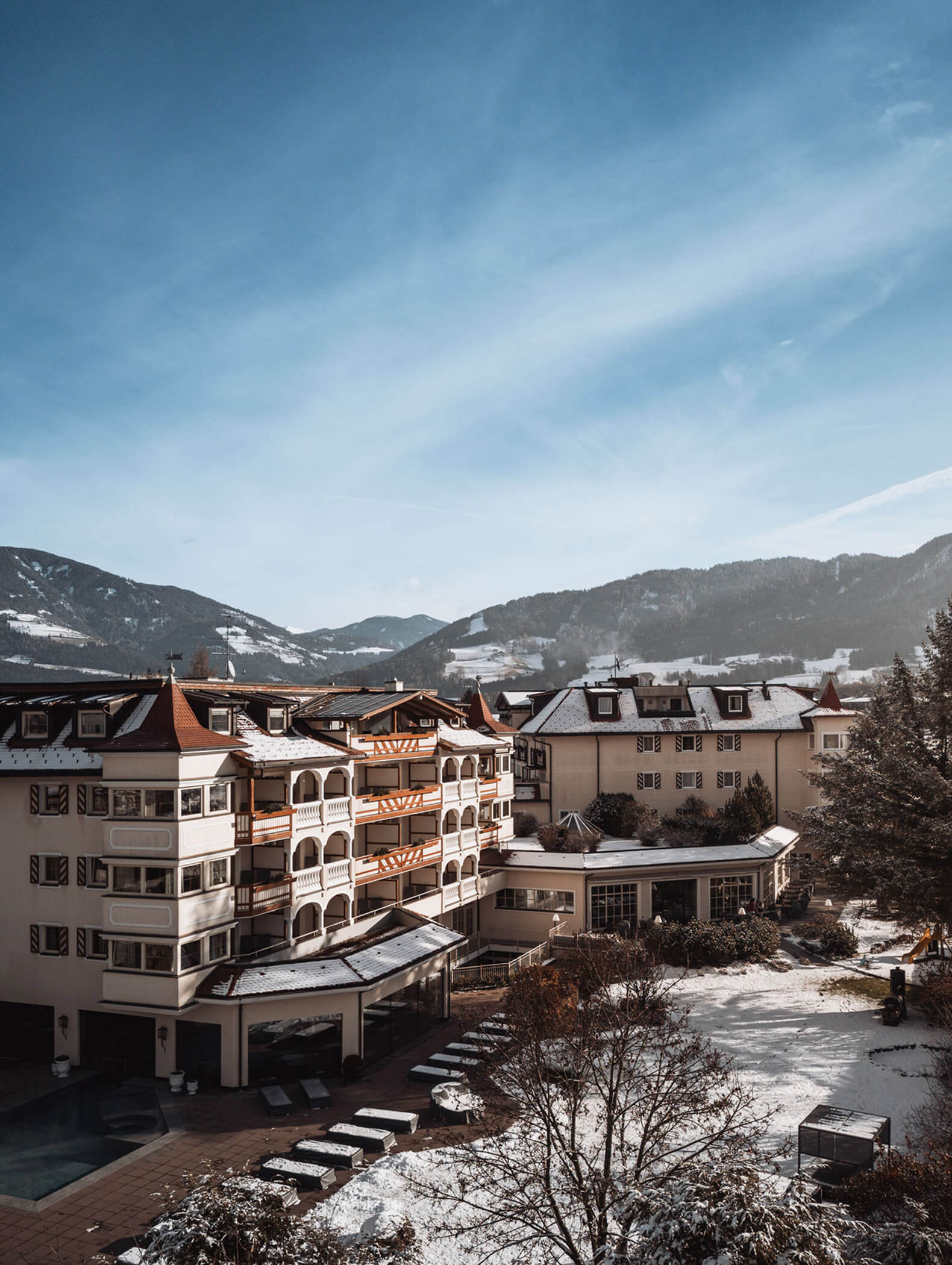 Frau spaziert entlang vom Rand des Pools, die Landschaft rundherum ist verschneit - Hotel Majestic