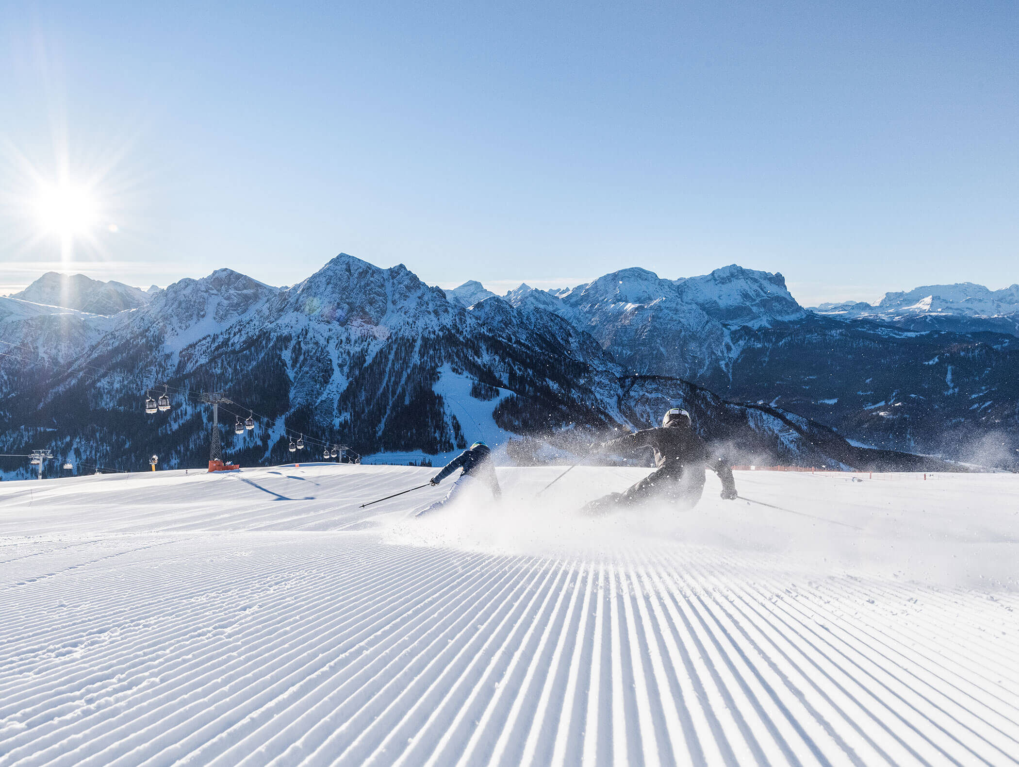 Skifahrer fahren die Piste in den Dolomiten hinunter, der Schnee wirbelt auf - Hotel Majestic